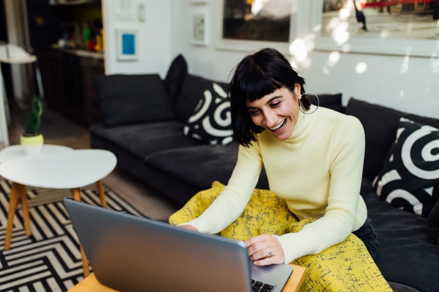 Woman wearing yellow using a laptop and trying to figure out how to choose an MBA program